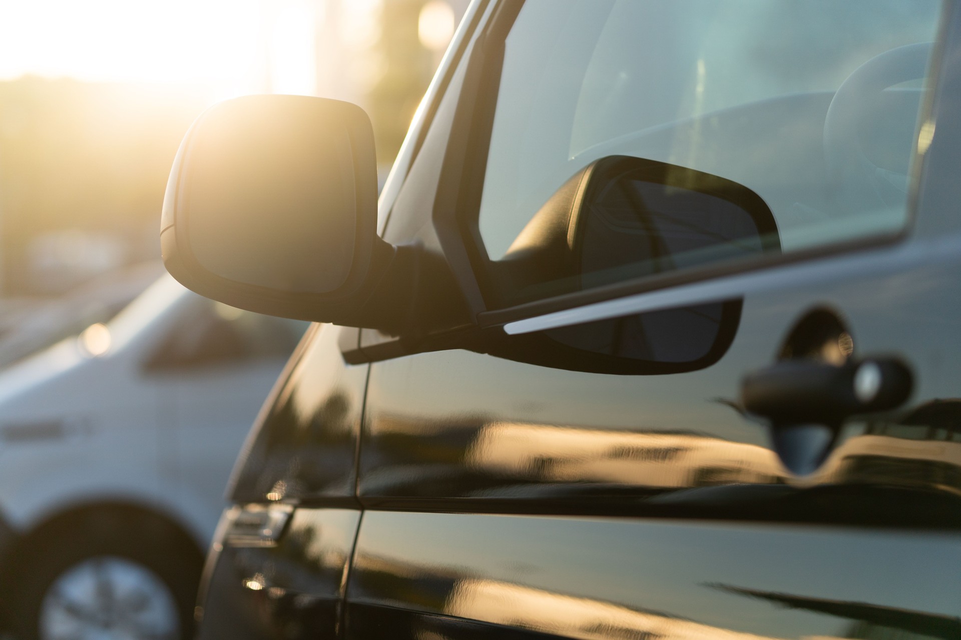 Black van side mirror against the light of the evening sun
